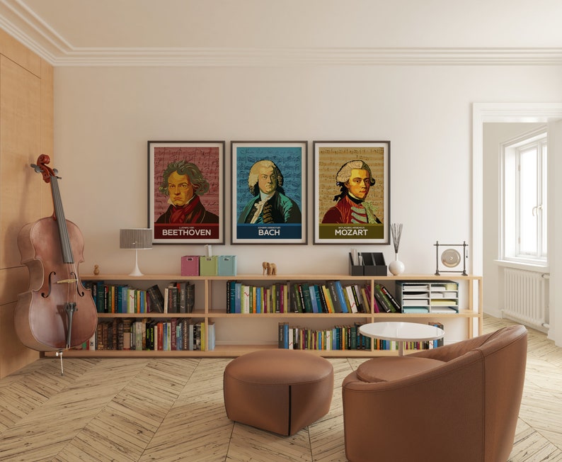 May include: Three framed posters of famous composers, Beethoven, Bach, and Mozart, with their portraits and musical notes in the background. The posters are hanging on a white wall above a bookshelf filled with books.