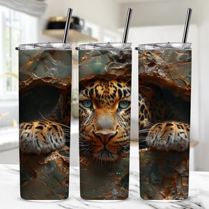 Könnte beinhalten: Drei Edelstahlbecher mit einem Design eines Leoparden, der hinter einem Felsen hervorlugt. Der Leopard hat braune und schwarze Flecken und blaue Augen.