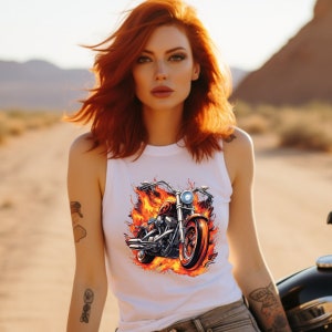May include: A white tank top with a graphic of a motorcycle engulfed in flames. The motorcycle is silver and black with a red seat. The flames are orange and yellow.