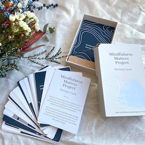 May include: A set of blue and white mindfulness cards with the text "Mindfulness Matters Project The Daily Cards" on the front. The cards are in a white box with the same text on the front.