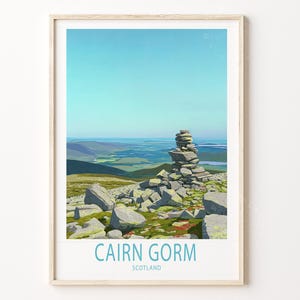 May include: A framed print of Cairn Gorm in Scotland. The artwork depicts a stack of stones on a mountain peak, with a blue sky and green landscape in the background. The text "CAIRN GORM SCOTLAND" is at the bottom.
