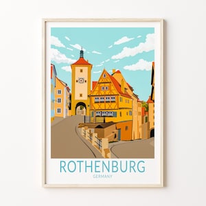 Può includere: Una stampa artistica incorniciata con un'illustrazione colorata di Rothenburg, Germania. L'opera raffigura una scena di strada con edifici nei toni del giallo, arancione e blu, sotto un cielo azzurro con nuvole. La parola "ROTHENBURG" è stampata in basso.