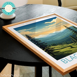 May include: A framed print of a mountain landscape with a blue sky and white clouds. The mountains are green and the foreground is a forest of pine trees. The text "BLACK" is visible in the bottom right corner of the print.