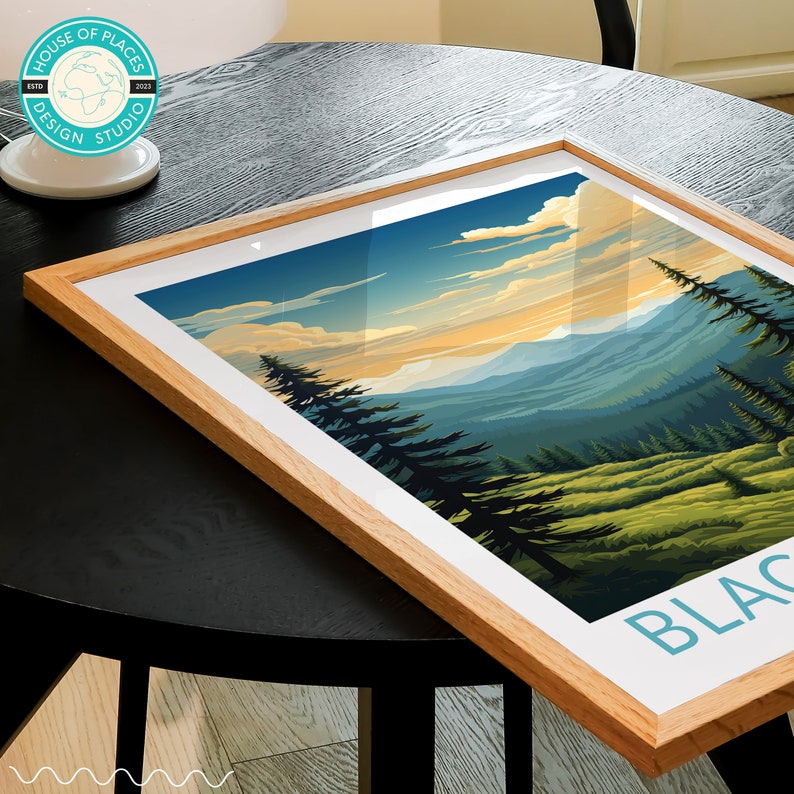 May include: A framed print of a mountain landscape with a blue sky and white clouds. The mountains are green and the foreground is a forest of pine trees. The text "BLACK" is visible in the bottom right corner of the print.