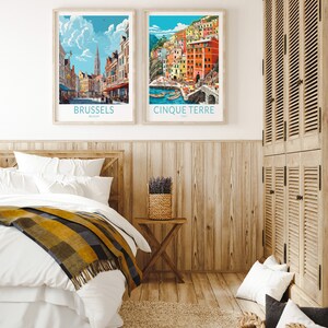 K&ouml;nnte beinhalten: Zwei gerahmte Reiseposter h&auml;ngen an einer Holzwand. Das Poster links zeigt eine Stadtansicht von Br&uuml;ssel, Belgien. Das Poster rechts zeigt eine Stadtansicht von Cinque Terre, Italien.
