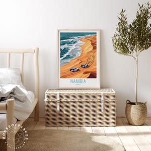 K&ouml;nnte beinhalten: Ein Poster mit einer farbenfrohen Illustration einer Strandszene in Namibia, Afrika. Zwei wei&szlig;e Fahrzeuge fahren auf den Sandd&uuml;nen. Das Poster tr&auml;gt den Text "NAMIBIA" und "AFRICA".