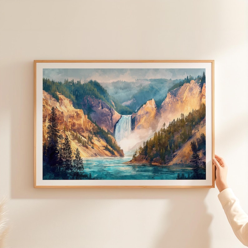 Op de afbeelding: Een ingelijste aquarelprint van een schilderachtig landschap met een waterval die in een turquoise rivier stort. Het kunstwerk toont torenhoge kliffen, weelderige groene bossen en een mistige lucht, alles in een natuurlijke houten lijst.
