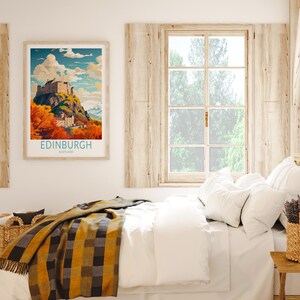 May include: A framed poster with a vintage travel illustration of Edinburgh Castle in Scotland. The poster has a blue and white border and the text "EDINBURGH SCOTLAND" at the bottom. The poster is hanging on a white wall above a bed with white bedding and a yellow and black plaid throw blanket.