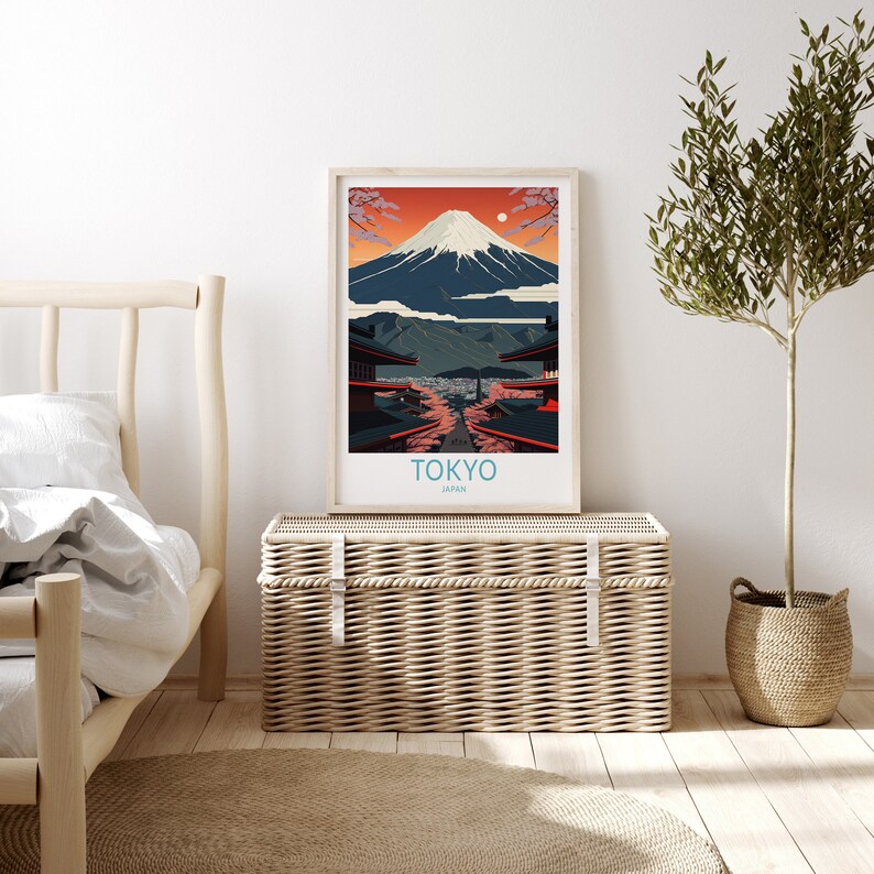 Pu&ograve; includere: Un poster minimalista con un'illustrazione grafica del Monte Fuji, uno skyline urbano e il testo "TOKYO, GIAPPONE". Il poster &egrave; incorniciato e appeso a una parete bianca sopra uno scrigno di vimini.