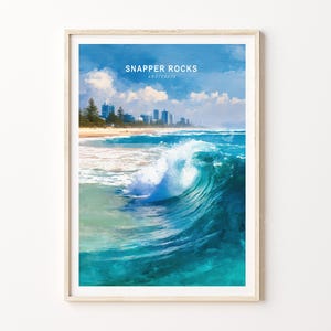 May include: Framed art print of Snapper Rocks, Australia. The artwork depicts a vibrant ocean wave in shades of turquoise and blue, with a sandy beach and buildings in the background. The sky is a bright blue with fluffy white clouds.