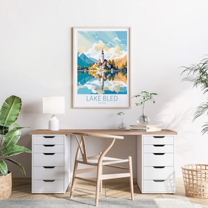 Op de afbeelding: Een minimalistisch thuiskantoor met een wit bureau en een houten stoel. Een ingelijst poster met een kleurrijke illustratie van het meer van Bled, Sloveni&euml;, hangt aan de muur boven het bureau. De poster luidt "Lake Bled, Sloveni&euml;".