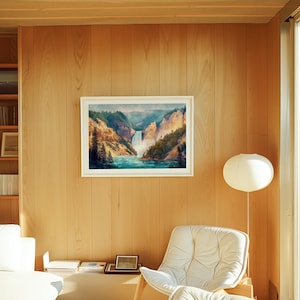 Op de afbeelding: Een ingelijst landschapsschilderij van een waterval en een kloof hangt aan een met hout beklede muur. Het kunstwerk toont een waterval die in een turquoise rivier stort, omgeven door groene bomen en gouden kliffen. Een witte stoel en lamp staan in de kamer.