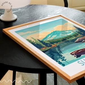 May include: A framed print of a mountain lake scene with a boat in the water. The print is in a light wood frame and has a white background. The text "Sunrise" is at the bottom of the print.