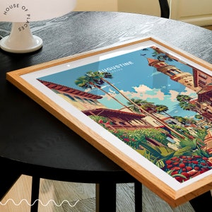 May include: A framed print of a colorful illustration of St. Augustine, Florida. The illustration depicts a street scene with palm trees, buildings, and a blue sky.