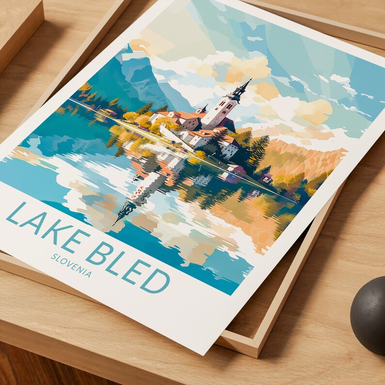 Op de afbeelding: Een kleurrijke illustratie van het meer van Bled in Sloveni&euml;, met een kerk op een eiland in het meer, omringd door bergen en weerspiegeld in het water. De tekst "LAKE BLED" en "SLOVENIA" staat onder de afbeelding.