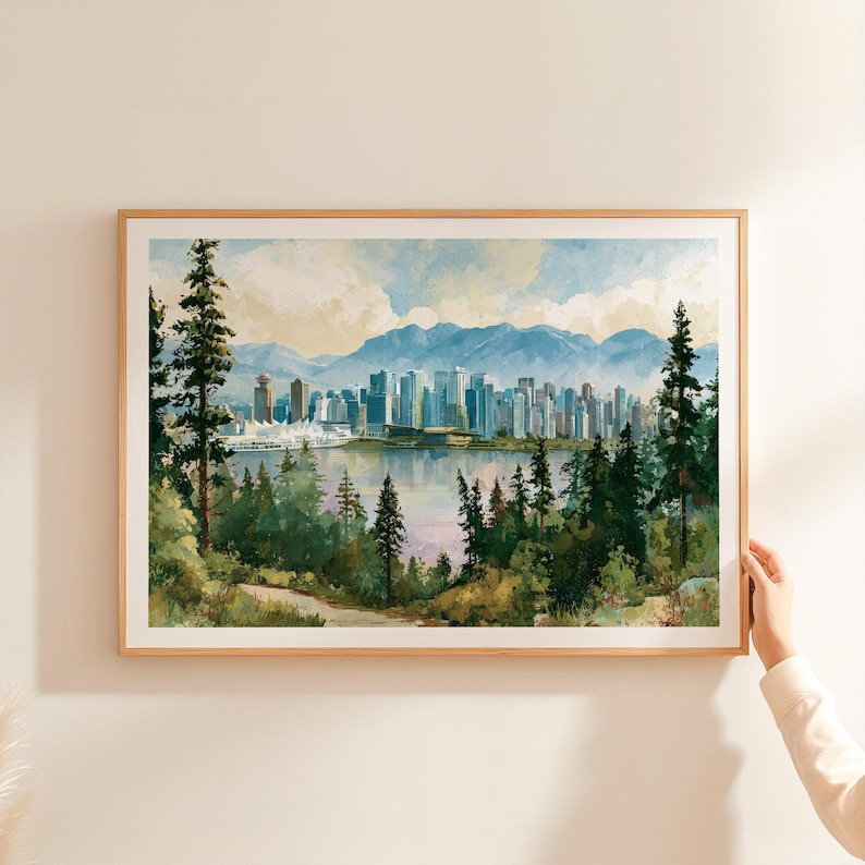 May include: A framed landscape print featuring a watercolour-style city skyline across a body of water, framed by tall evergreen trees in the foreground and distant blue mountains under a soft, cloudy sky with light blue and cream tones.