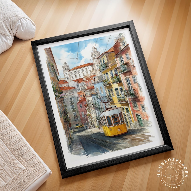 Pu&ograve; includere: Stampa artistica incorniciata di una scena di strada di Lisbona con un tram giallo sui binari, edifici colorati e una chiesa sullo sfondo. L'opera d'arte &egrave; in una cornice nera ed &egrave; appoggiata su una superficie di legno. La stampa &egrave; di House of Places California.