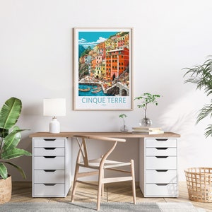 K&ouml;nnte beinhalten: Ein gerahmtes Poster mit einer farbenfrohen Illustration einer Stadt an einem Kliff mit dem Text "Cinque Terre, Italien" unten.