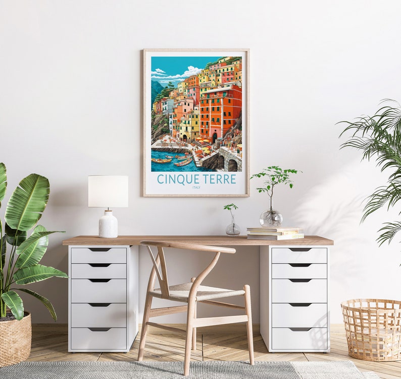 K&ouml;nnte beinhalten: Ein gerahmtes Poster mit einer farbenfrohen Illustration einer Stadt an einem Kliff mit dem Text "Cinque Terre, Italien" unten.