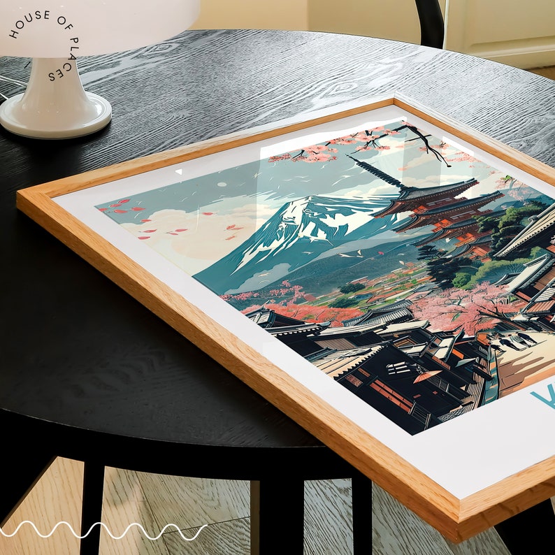 Puede incluir: Una impresi&oacute;n enmarcada de un paisaje japon&eacute;s con el monte Fuji en el fondo. La impresi&oacute;n presenta una pagoda, flores de cerezo y casas tradicionales japonesas. La impresi&oacute;n est&aacute; en un marco de madera.
