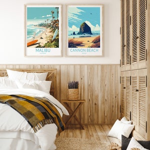 Puede incluir: Dos p&oacute;sters de viaje enmarcados con ilustraciones de escenas de playa. El p&oacute;ster de la izquierda muestra una playa en Malib&uacute;, California, con palmeras y surfistas. El p&oacute;ster de la derecha muestra una playa en Cannon Beach, Oreg&oacute;n, con una gran formaci&oacute;n rocosa en el agua.