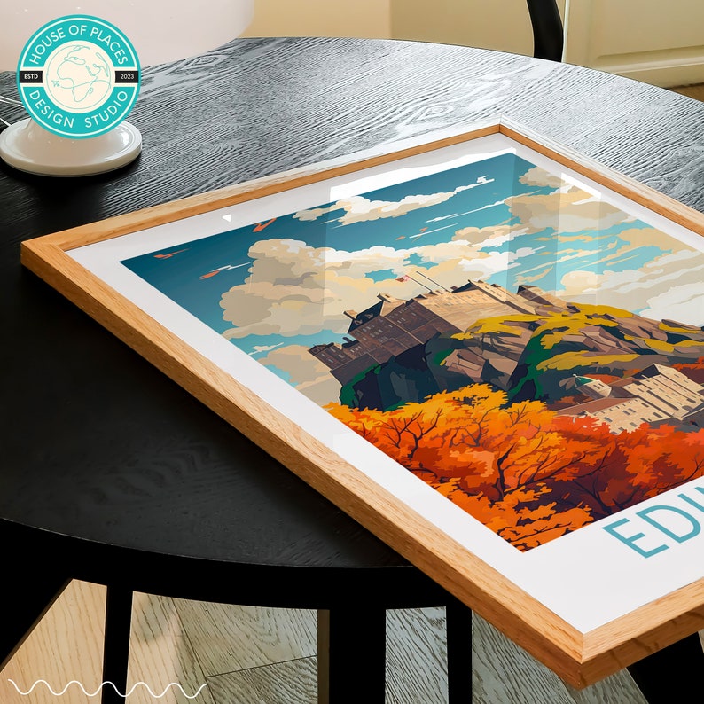 May include: A framed print of Edinburgh Castle in Scotland. The castle is perched on a rocky hilltop with a backdrop of blue sky and fluffy white clouds. The print features a vibrant color palette with autumnal foliage in shades of orange, yellow, and red.