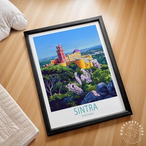 May include: Framed art print showing a colourful illustration of Sintra, Portugal. The artwork depicts a vibrant palace atop a hill, surrounded by lush greenery and rocks, under a clear blue sky. The word "Sintra" is displayed in teal font.