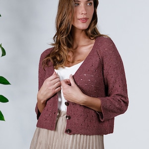 Könnte beinhalten: Ein maroner Cardigan mit V-Ausschnitt und Knopfleiste. Der Cardigan hat ein zartes Lochmuster und Dreiviertelärmel.