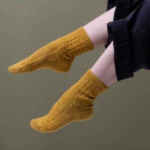 Puede incluir: Un par de calcetines de color amarillo mostaza con un patrón de punto texturizado.