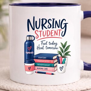 May include: A white ceramic mug with a dark blue rim and handle, featuring the text "NURSING STUDENT" and "Fuel today. Heal tomorrow." The graphic includes a blue water bottle, a stack of books labeled Anatomy, Pharmacology, Pathophysiology, and Nursing Care, a potted plant, and pens.