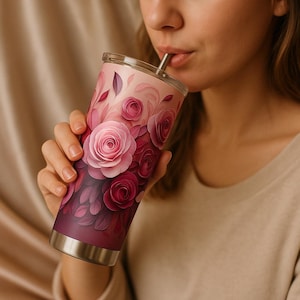 May include: A stainless steel tumbler with a pink and purple floral design. The tumbler has a lid and a straw.
