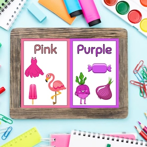 May include: Two flashcards with the words "Pink" and "Purple" written on them. Each card has pictures of objects in the corresponding color. The pink card has a dress, a popsicle, and a flamingo. The purple card has a candy, a radish, and an onion.