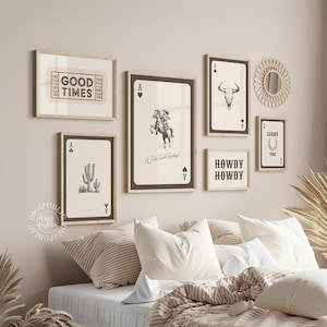 May include: A gallery wall featuring framed art prints with a Western theme. The prints include playing card designs with a cactus, a cowboy on a horse, and a bull skull. One print reads "GOOD TIMES," and another says "HOWDY HOWDY."