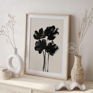 Framed digital artwork of abstract black flowers created with bold brush strokes on a light background, minimalist botanical printable wall art.