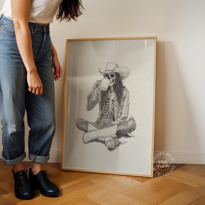May include: A framed pencil drawing depicts a skeleton wearing a cowboy hat and jacket, seated cross-legged, drinking from a mug. The artwork has a light beige background and is displayed on a wooden floor.
