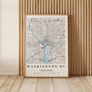 May include: A framed map print of Washington DC, United States, featuring a light beige background with black street lines and a light blue river. The text reads WASHINGTON DC, UNITED STATES, and the coordinates 38.9072 N / 77.0369 W.