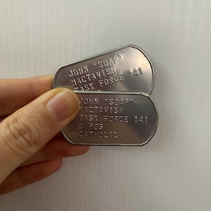 May include: Two silver dog tags with the text "JOHN SOAP MACTAVISH TASK FORCE 141" and "O POS CATHOLIC" on them.