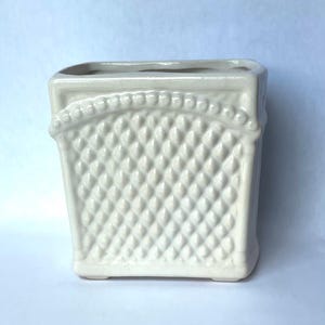 May include: A square, off-white ceramic planter featuring a raised, diamond-shaped lattice texture on the front panel. The top edge is bordered by a decorative row of small, rounded beads, and the entire piece has a smooth, glossy finish.