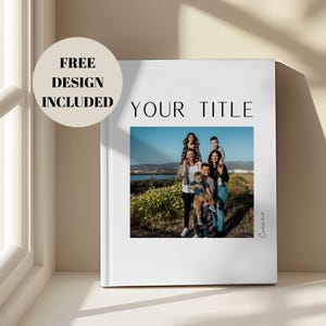 Peut inclure: Un livre blanc avec les mots "YOUR TITLE" et une photo de famille. Le livre a un autocollant circulaire qui dit "FREE DESIGN INCLUDED". La photo montre une famille de six personnes à l'extérieur.