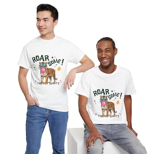 May include: White t-shirts featuring a cartoon tiger wearing sunglasses and blowing a bubblegum bubble. The text on the shirt says "ROAR SOME!" and "TINY BUT MIGHTY".