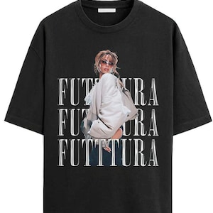 Puede incluir: Camiseta negra con la palabra "FUTTURA" en blanco, repetida tres veces verticalmente. La camiseta presenta una foto de una persona con gafas de sol y una chaqueta blanca.