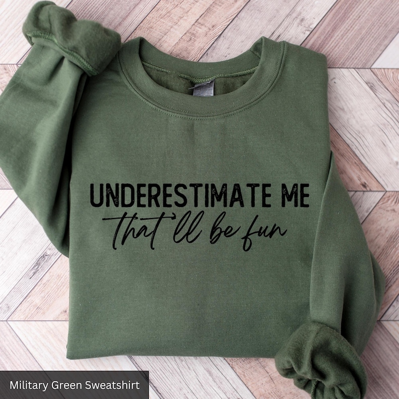 a green sweatshirt that says, underestimate me that'll be fun