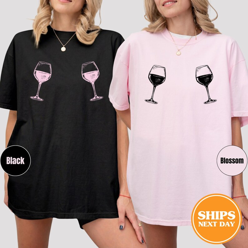 May include: Black and pink t-shirts with a wine glass graphic. The black shirt has a pink wine glass graphic, and the pink shirt has a black wine glass graphic. The shirts are oversized and comfortable.
