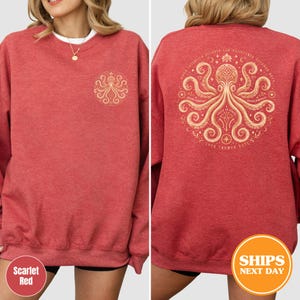 Puede incluir: Sudadera roja escarlata con un dise&ntilde;o de pulpo dorado en la parte delantera y trasera. El dise&ntilde;o trasero es una ilustraci&oacute;n detallada de un pulpo dentro de un marco circular, con el texto "LOVE TRUMPS HATE".