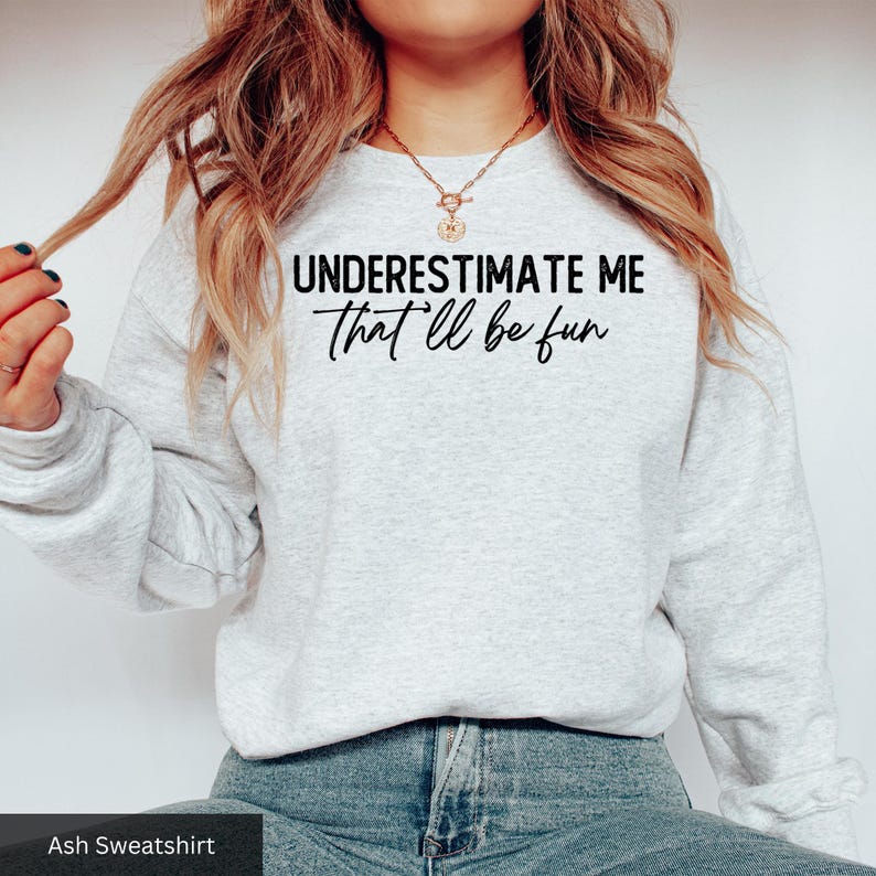 a woman wearing a sweatshirt that says, underestimate me that'll