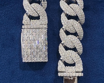 May include: A silver chain bracelet with a large, chunky, Cuban link design. The bracelet is fully encrusted with small, clear, round-cut diamonds.