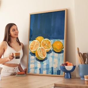 May include: A framed painting of lemons on a blue and white checkered tablecloth. The lemons are yellow and have a glossy finish. The painting is set against a dark blue background.