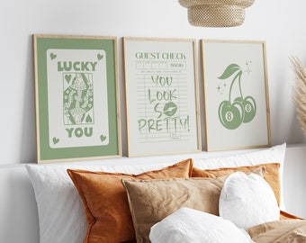 May include: Three framed prints with green illustrations on a white background. The first print features a queen of hearts playing card with the text "Lucky You". The second print features a guest check with the text "You Look So Pretty!". The third print features two cherries with the number 8 on them.
