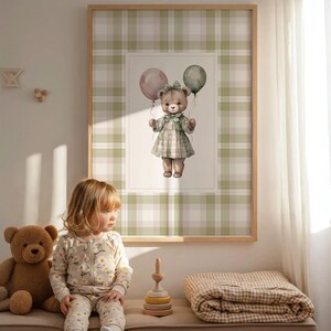 May include: A framed print of a teddy bear holding balloons, set against a green and white plaid background. A child in a daisy-print onesie sits on a bench with a teddy bear and a wooden stacking toy. A plaid blanket is also on the bench.