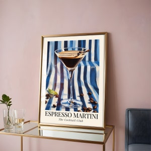 May include: A framed print of an espresso martini cocktail in a martini glass. The drink is on a blue and white striped background with coffee beans scattered around the glass. The text "Espresso Martini The Cocktail Club" is at the bottom of the print.